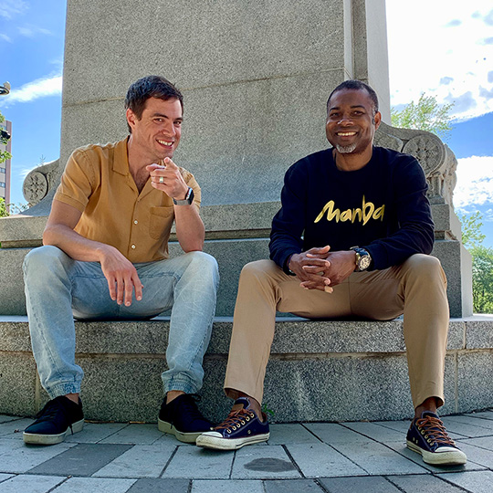 Stanley Dumornay and Jason Delis sitting by a statue